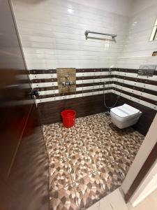 a bathroom with a toilet and a red bucket at Staio Rooms in Thodupuzha