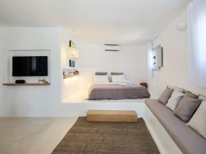 a white bedroom with a bed and a couch at myMykonos Guest House in Platis Gialos