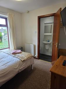 a bedroom with a bed and a window and a sink at Beeches Guest House in Dyce