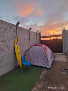 a tent and a surfboard leaned against a wall at Tampu Machi Eco Camping in Chancayllo