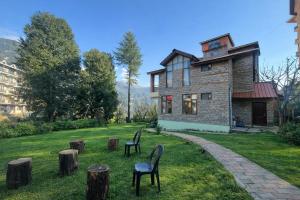 an old house with two chairs in the yard at 4 Bedroom Luxury Bungalow In Manali With Beautiful Scenic Mountain & Orchard View - #Private Bungalow #Premium Big rooms #Parking #Guest Preferred in Manāli