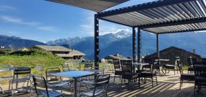 a patio with tables and chairs with mountains in the background at Le Shantoné in Saint-Michel-de-Maurienne