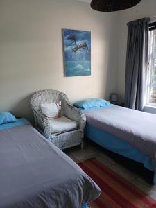 a bedroom with two beds and a chair and a window at Dollery House in Port Alfred