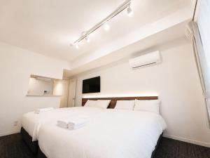 a bedroom with a large white bed with white sheets at Hotel ONE'S RESIDENCE in Sapporo