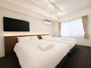 a hotel room with two beds and a flat screen tv at Hotel ONE'S RESIDENCE in Sapporo