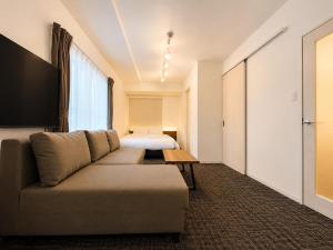 a living room with a couch and a bed at Hotel ONE'S RESIDENCE in Sapporo