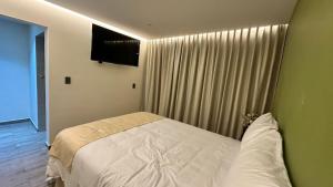 una camera da letto con un letto bianco e una parete verde di CORTZA Hotel a Città del Messico