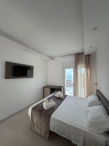 a white bedroom with a bed with towels on it at Albergo Diomedee Rooms on the Beach in Rodi Garganico