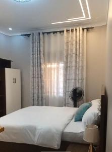 a bedroom with a bed and a window with curtains at Dephil stays in Jinja