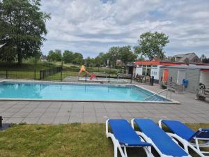 a swimming pool with chairs and a playground at vacation home 68 in Tzummarum +13 photos