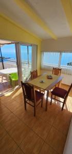 a dining room with a table and chairs and the ocean at Maca apartmani in Utjeha