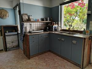 a kitchen with blue cabinets and a large window at B&B Hestia's Hideaway in Kalívia Thorikoú