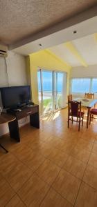 a living room with a television and a table and chairs at Maca apartmani in Utjeha