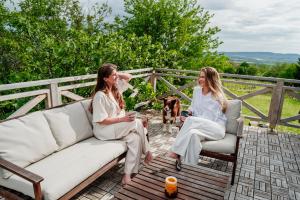 two women sitting on a couch with a dog at Baglyashegy Vendégház in Sümeg