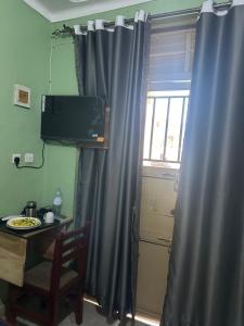 a room with a table and a window with a curtain at Zone hotel and guest house in Bugembe
