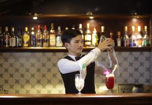 a man standing at a bar making a drink at The Heritage Courtyard in Siem Reap