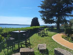 a row of tables and chairs on the grass near the water at Apartments Vila Toni in Portorož
