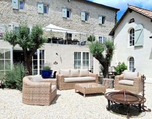 a patio with wicker chairs and a table and a building at Le Clos des Troubadours in Pennautier