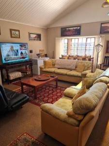 a living room with couches and a flat screen tv at The Blue Swallow in Kaapsehoop