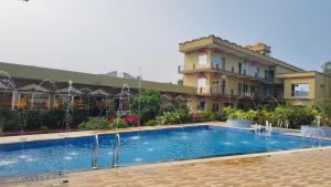 a hotel with a swimming pool in front of a building at RESORT SAIKAT SARANYA in Mandarmoni