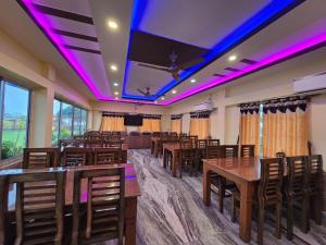 a banquet hall with tables and chairs and purple lights at RESORT SAIKAT SARANYA in Mandarmoni