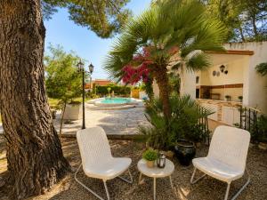 two chairs and a table next to a tree at AmetllaDeMar in Les tres Cales