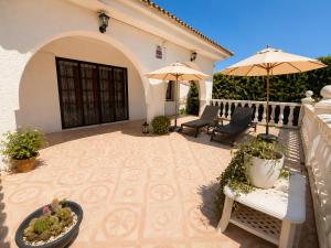 a patio with two umbrellas and a bench and chairs at AmetllaDeMar in Les tres Cales