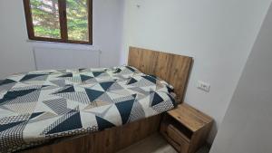 a bedroom with a bed with a black and white quilt at Pine Apartments Mavrovo in Mavrovo