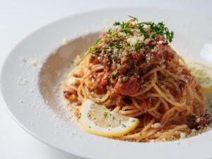 a plate of pasta with meat and a lemon slice at Premier Hotel-CABIN-Sapporo in Sapporo
