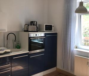a kitchen with a stove and a microwave on top of it at Ferienwohnung am Wald in Sebnitz