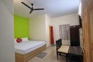 a bedroom with a bed and a table and a ceiling fan at Ashok Nandini Guest House in Bhubaneshwar