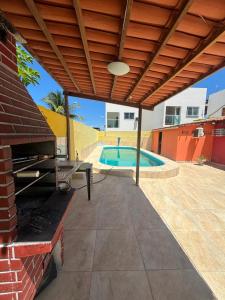 a patio with a wooden pergola and a swimming pool at Suítes Jacumã in Conde