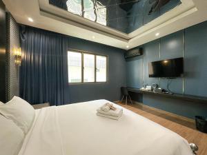 a bedroom with a large white bed with a tv at G Boutique Silom Hotel in Bangkok