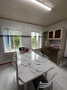 eine Küche mit einem großen weißen Tisch und Stühlen in der Unterkunft Arnas in Barskoon