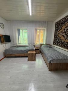 ein Schlafzimmer mit zwei Betten, einem Fernseher und zwei Fenstern in der Unterkunft Arnas in Barskoon