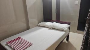 a bed with two white towels on top of it at Sasi Residency in Thiruchendur