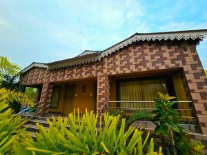a brick house with a yellow door and some plants at RESORT SAIKAT SARANYA in Mandarmoni