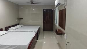two beds in a small room with a window at Sasi Residency in Thiruchendur