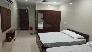 a bedroom with two beds and a bathroom with a mirror at Sasi Residency in Thiruchendur