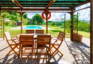 a wooden table and chairs on a patio with a pool at la villa bella vista in Castelmuzio