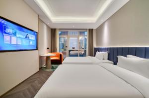 a hotel room with two beds and a flat screen tv at Ibis Styles Liyang Shanghecheng in Liyang