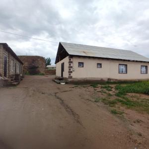 a building on a dirt road next to a field at Kamas Guesthouse in Kyzart