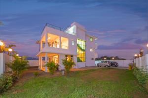 a large white house with a car parked in a yard at ll VIBE WITH US II BIG DADDY VILLA II 6BHK II AC II PRIVATE POOL II in Lonavala