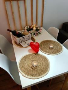 a white table with two plates and a candle and a red heart at 2R Relax Resort in Ubyszów