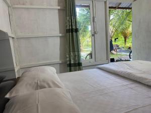 a bedroom with a white bed with a window at The Green Pearl Paradise in Biluhu