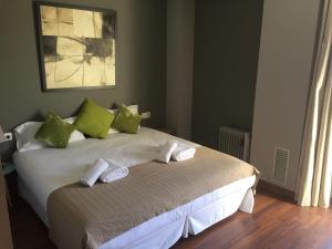 1 dormitorio con 1 cama con almohadas verdes y blancas en Apartamento FIRA Barcelona en Hospitalet de Llobregat