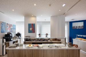 a kitchen with a counter with two people in the background at Harmony Bay Hotel in Limassol
