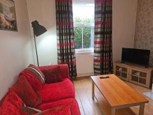 a living room with a red couch and a table at Nice 3 Bedroom House Ealing in London