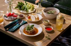 a wooden table topped with bowls of soup and food at Adela Hotel Dalat in Da Lat