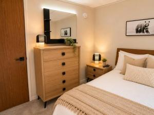 a bedroom with a bed and a dresser with a mirror at Modern North Van Escape with 2BR BBQ Workspace in North Vancouver